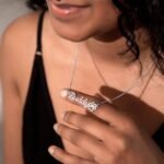 Model wearing a custom pet name necklace in stainless steel, showcasing the elegant design and paw charm
